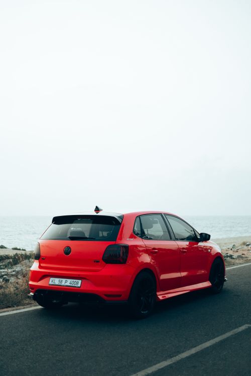 White Sky over a Red Car Parked on a Coastal Road · Free Stock Photo