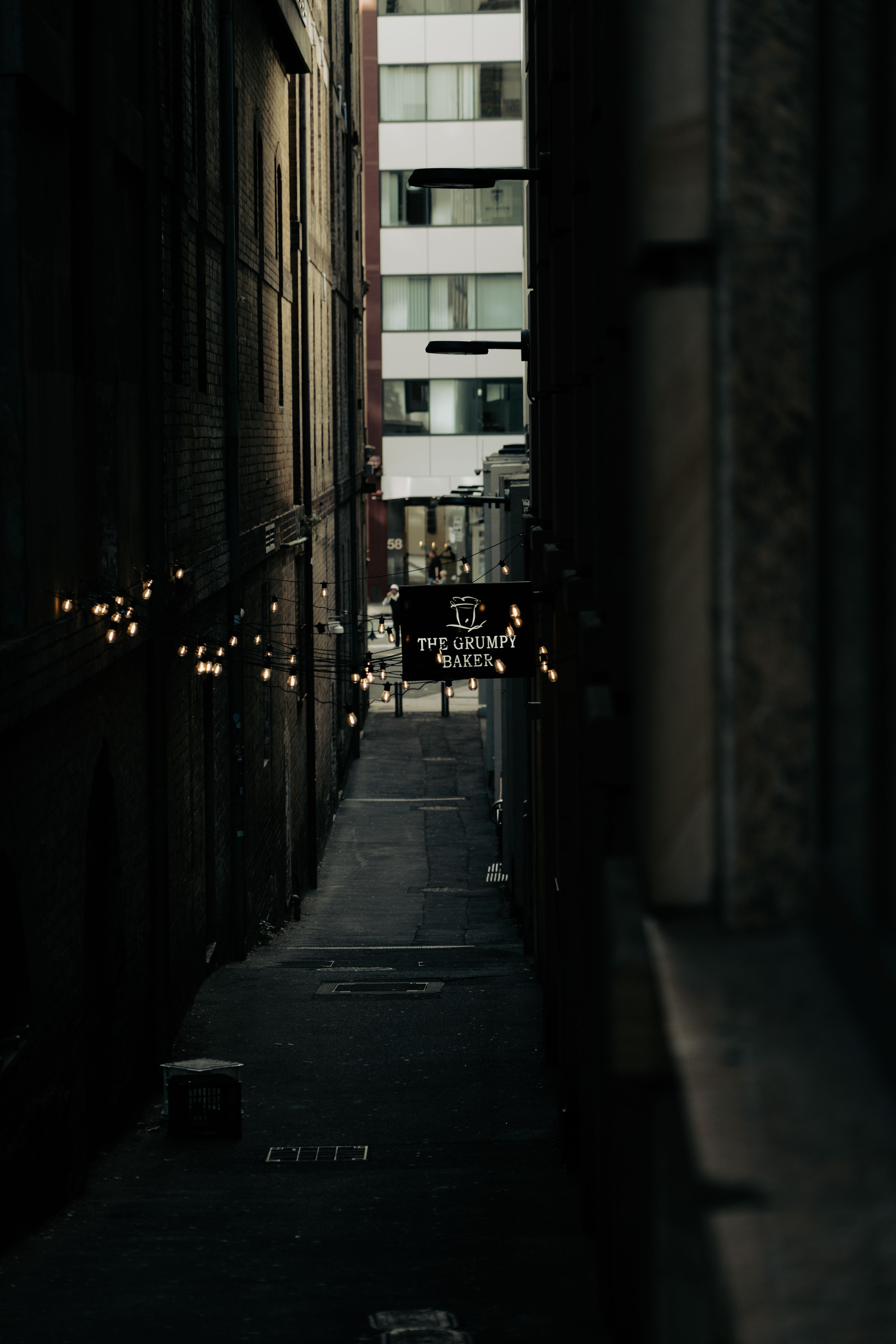 A dark alley with lights hanging from the ceiling · Free Stock Photo