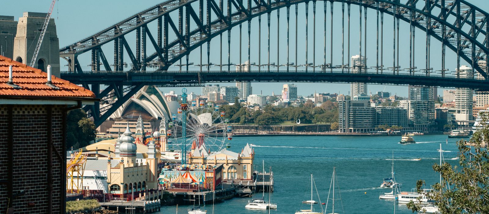 A vibrant view of Sydney Harbour Bridge with Luna Park and sailboats highlighting the iconic skyline. — flights from Nadi to Sydney