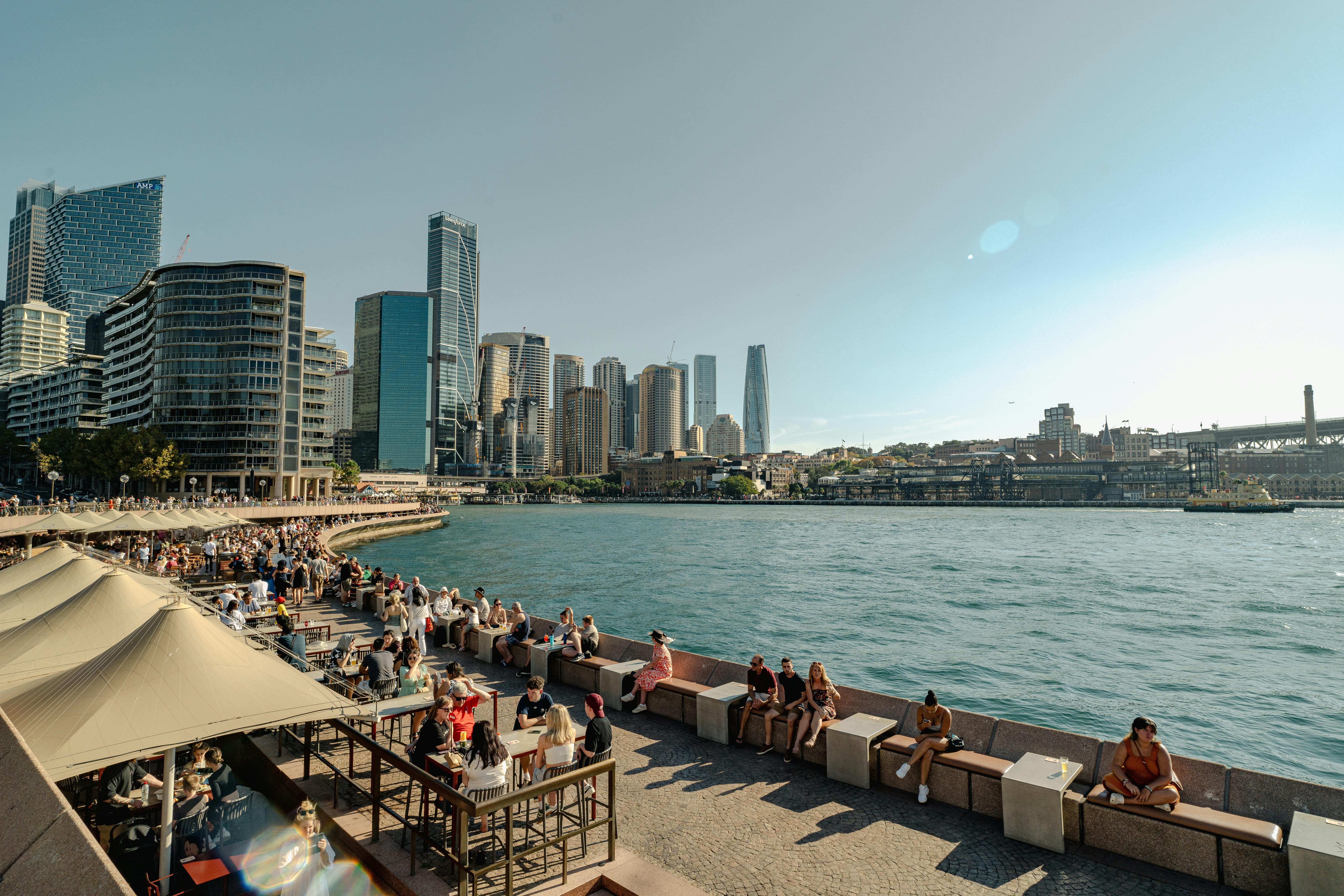 Vibrant scene of Sydney Harbour's waterfront with bustling crowds and iconic skyline.