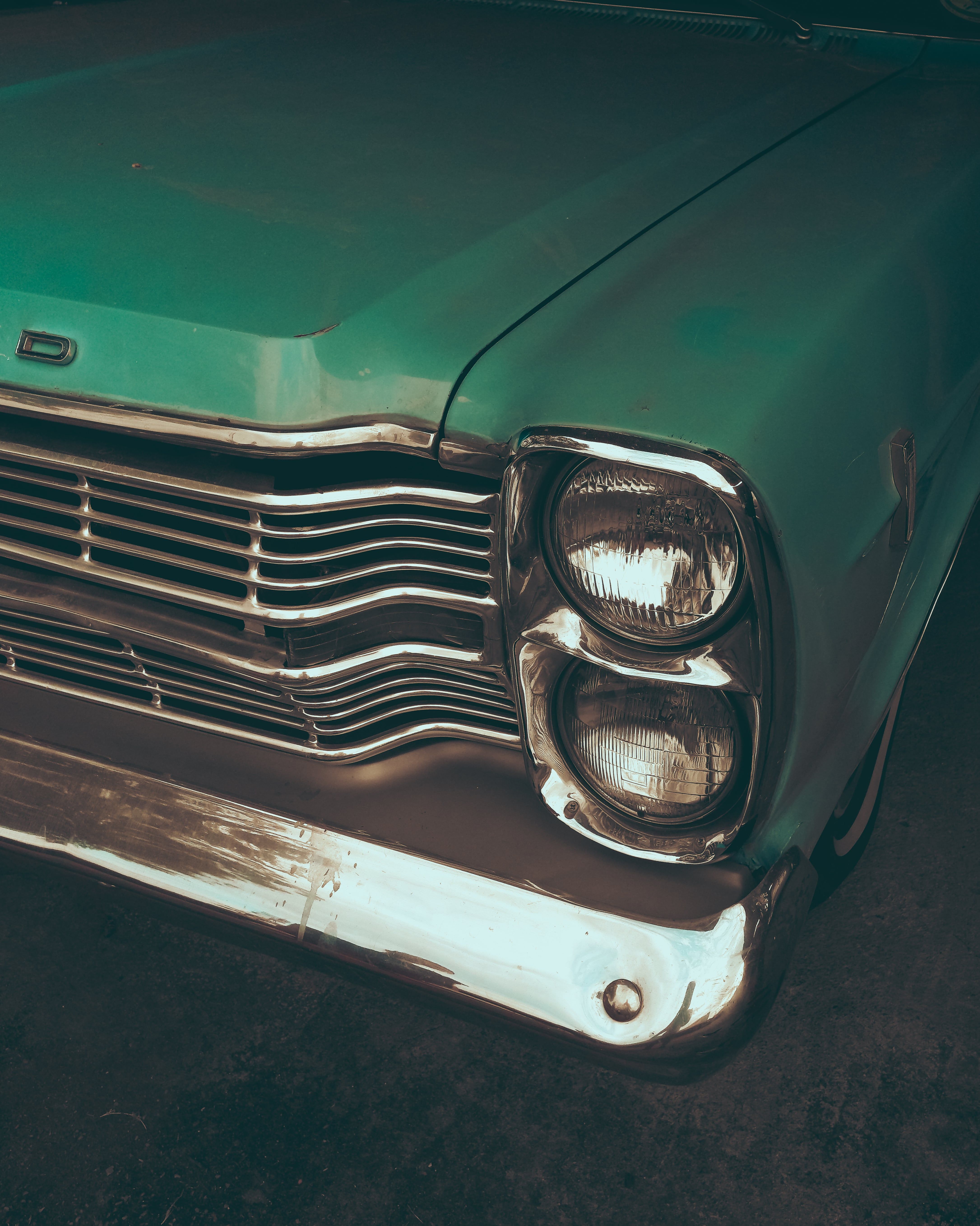 Detailed shot of a vintage teal car showcasing the front grille and headlight design.