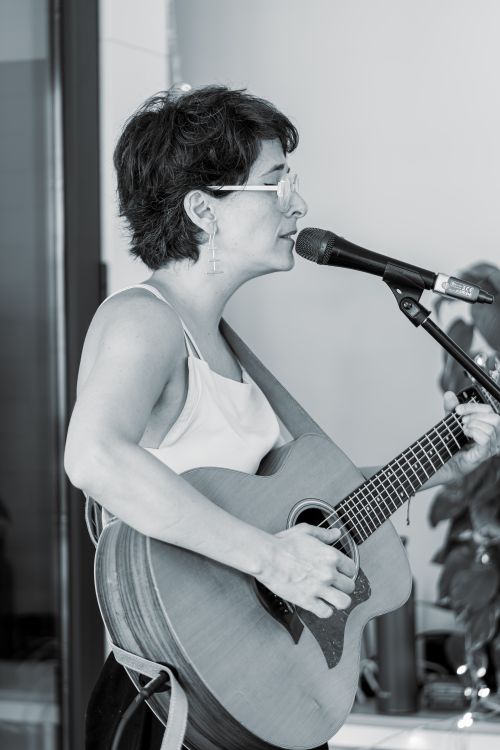 Free Side view of a woman singing and playing acoustic guitar indoors. Stock Photo