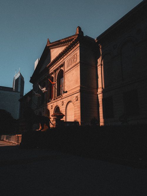Free A dramatic shot of a sunlit museum facade with towering skyline in the background. Stock Photo