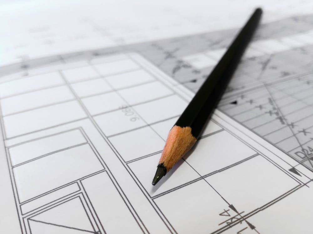 Close-up view of a pencil lying atop architectural plans for a building.