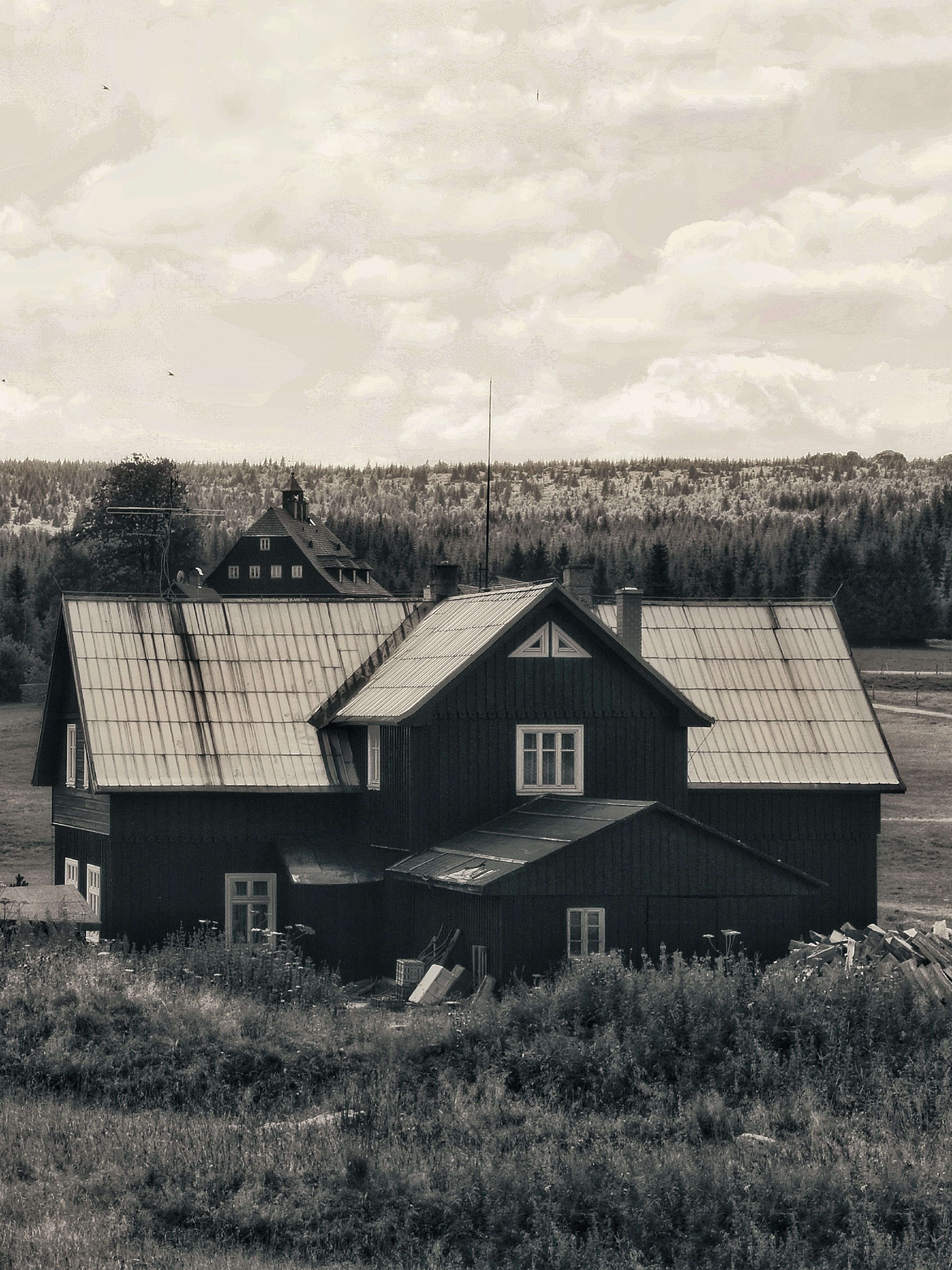 Vintage black and white image of a rustic farmhouse in a rural countryside setting.