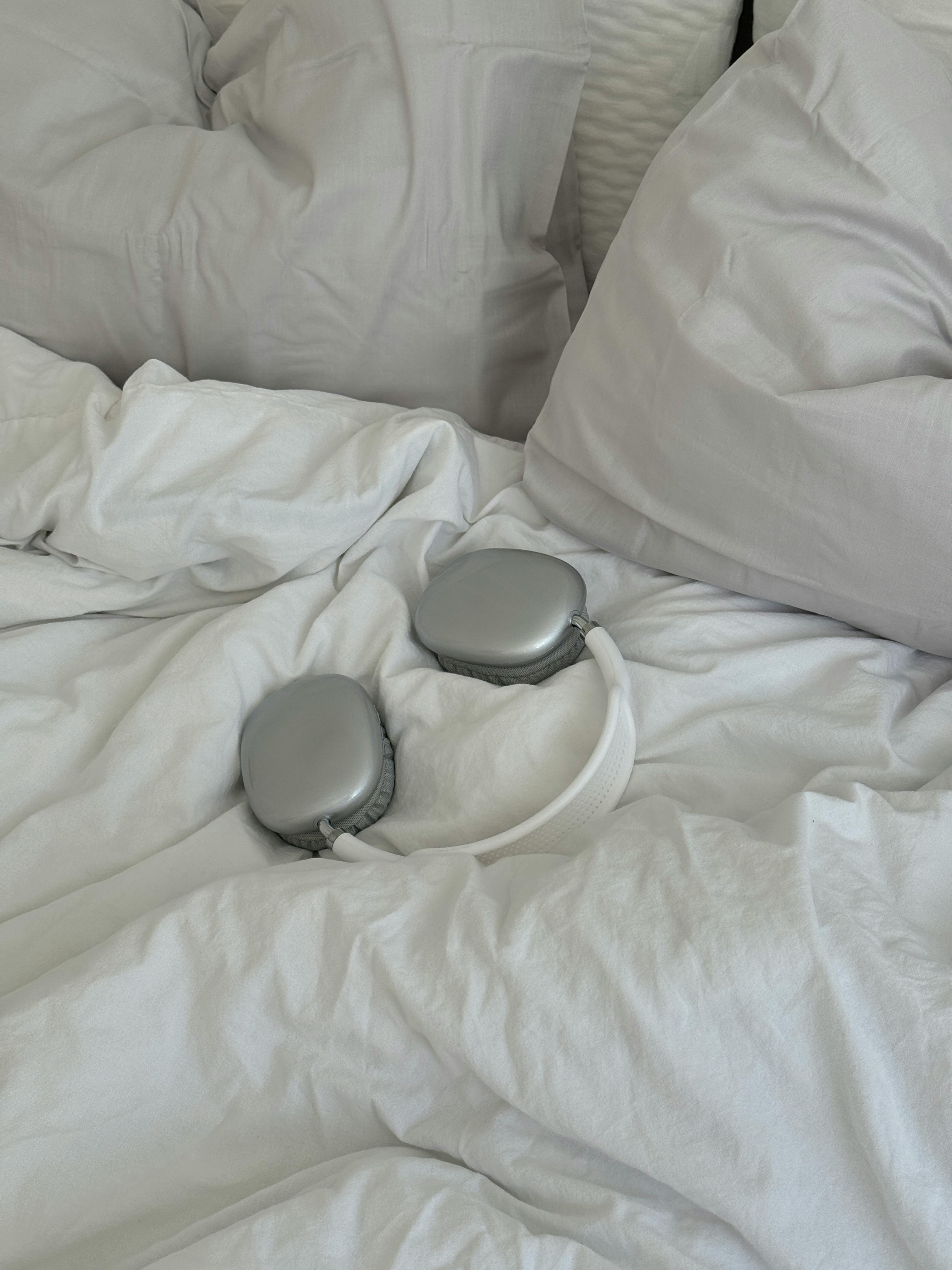 Cozy bedroom scene with luxury headphones on a bed with soft white pillows.