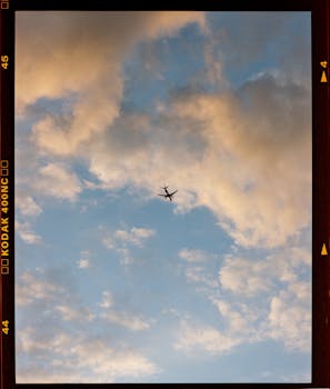 A lone airplane flies through a vibrant, cloud-filled sky, captured in a vertical shot.