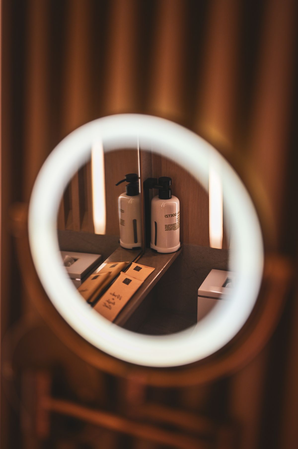 Bathroom mirror reflecting shampoo and body wash bottles on a shelf for bathroom cabinet organization ideas