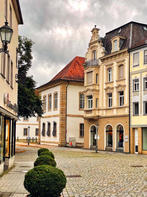 Free Cobblestone street lined with elegant, historic buildings under a cloudy sky in Europe. Stock Photo