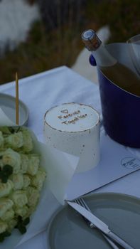 A minimalist outdoor table setting featuring a celebratory cake and wine, perfect for special occasions.