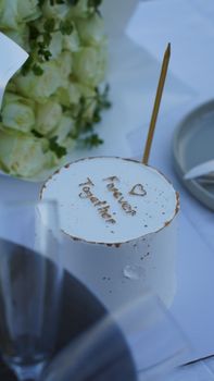 Close-up of a decorative wedding cake with 'Forever Together' inscription, shot outdoors.