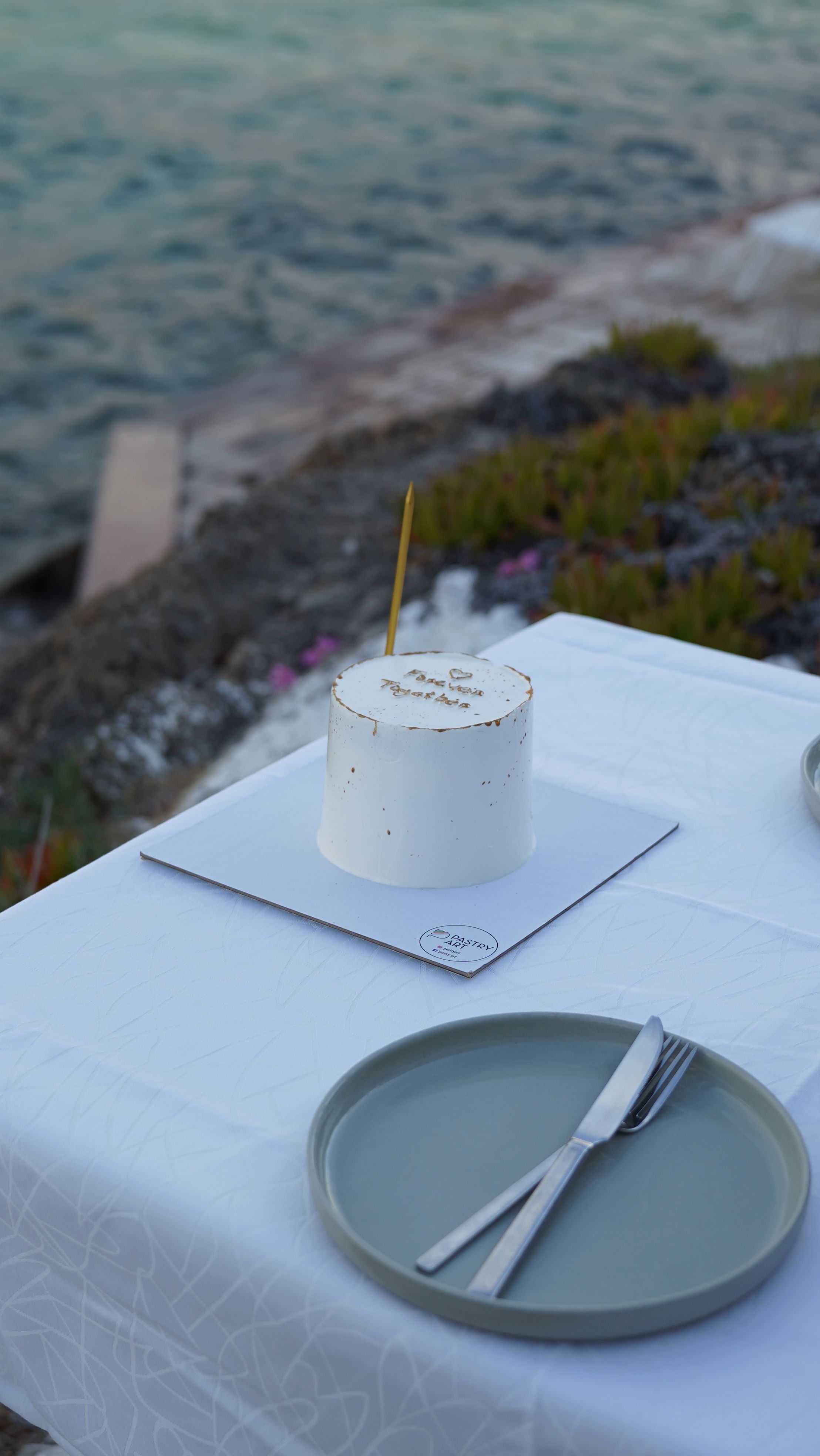 Minimalist cake on an outdoor table by the sea in Bozcaada, Türkiye.