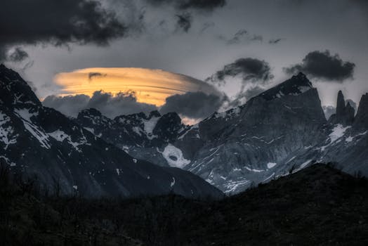 Majestic mountain peaks under striking cloud formations during twilight, creating a dramatic scene.