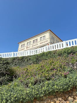 View of Restaurante Max Lindo against a bright blue sky in Silveira, Portugal. Vibrant greenery adds charm.