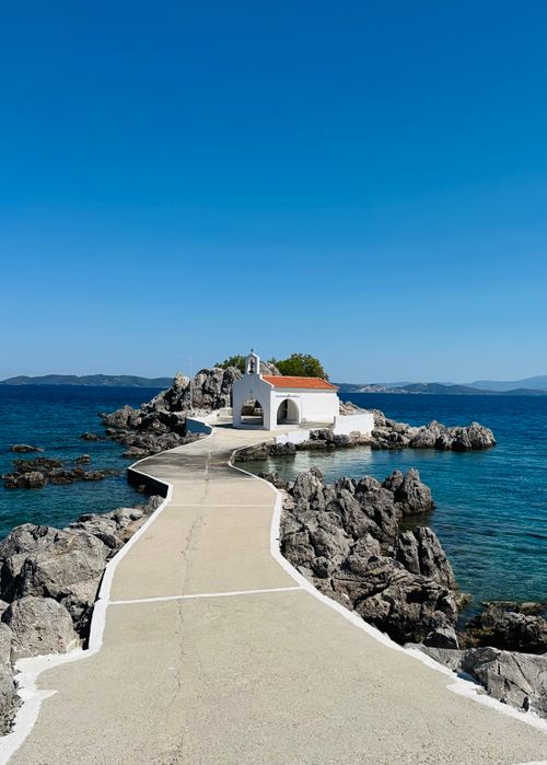 Free Picturesque path leading to Agios Isidoros Church in Chios, Greece, surrounded by blue sea. Stock Photo