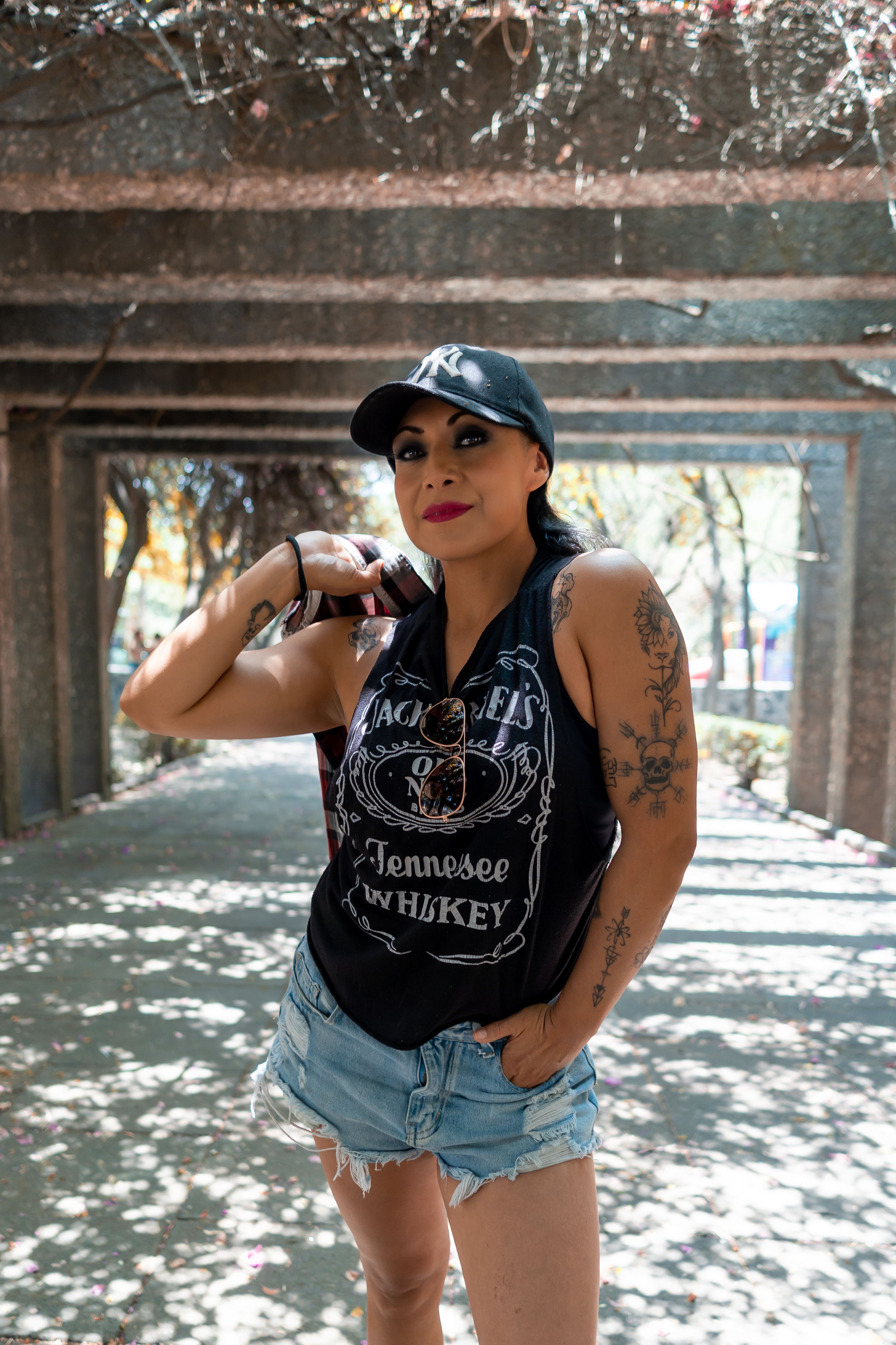 Fashionable woman with tattoos in shorts and cap, outdoors in sunny CDMX.