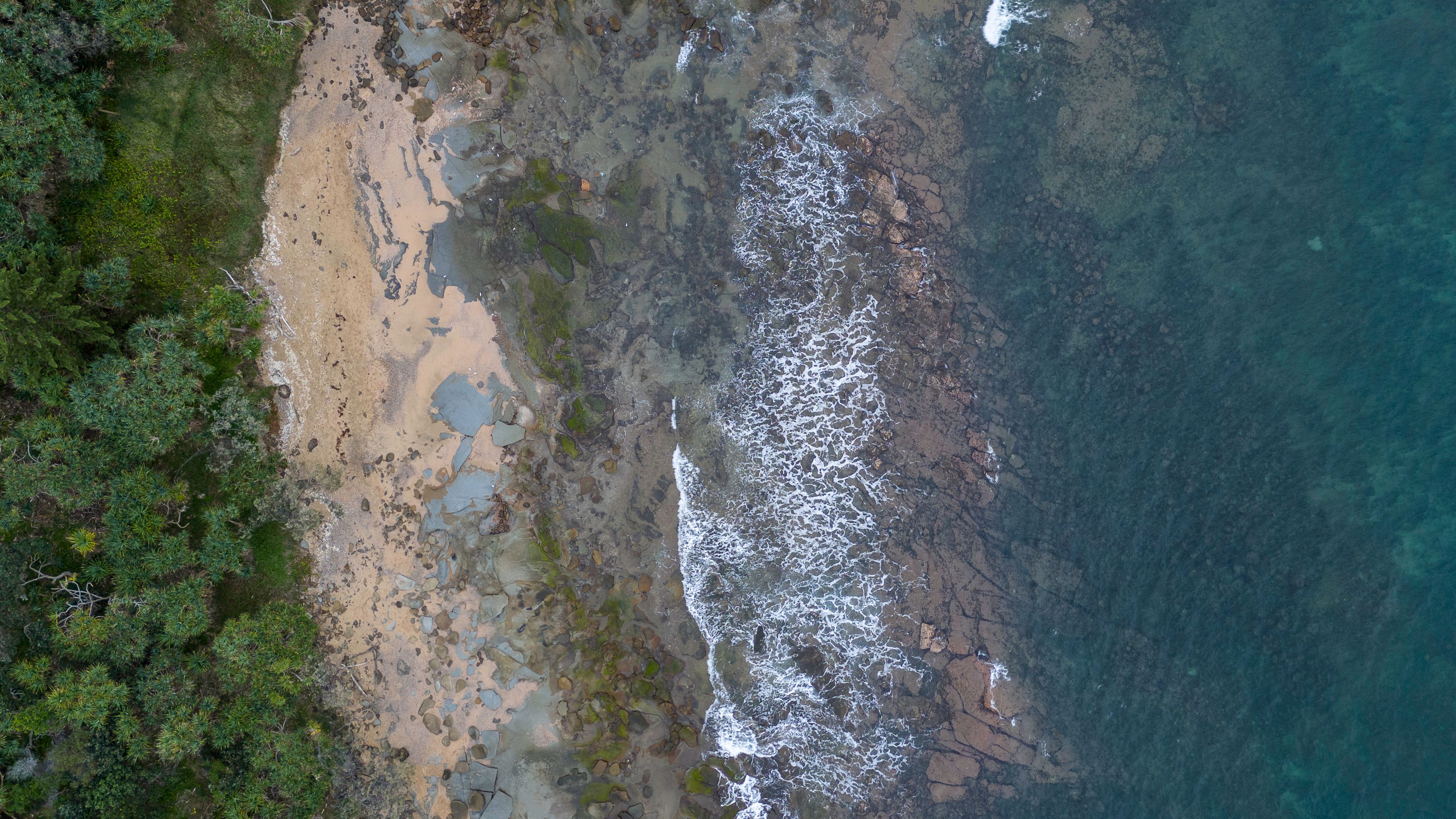 An aerial stretch of beach and surf, suggesting the scale of shoreline that authorities suddenly had to treat as a hazard scene.