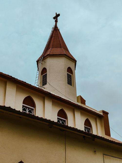 Free A traditional church tower with a cross against a cloudy sky, showcasing cultural architecture. Stock Photo