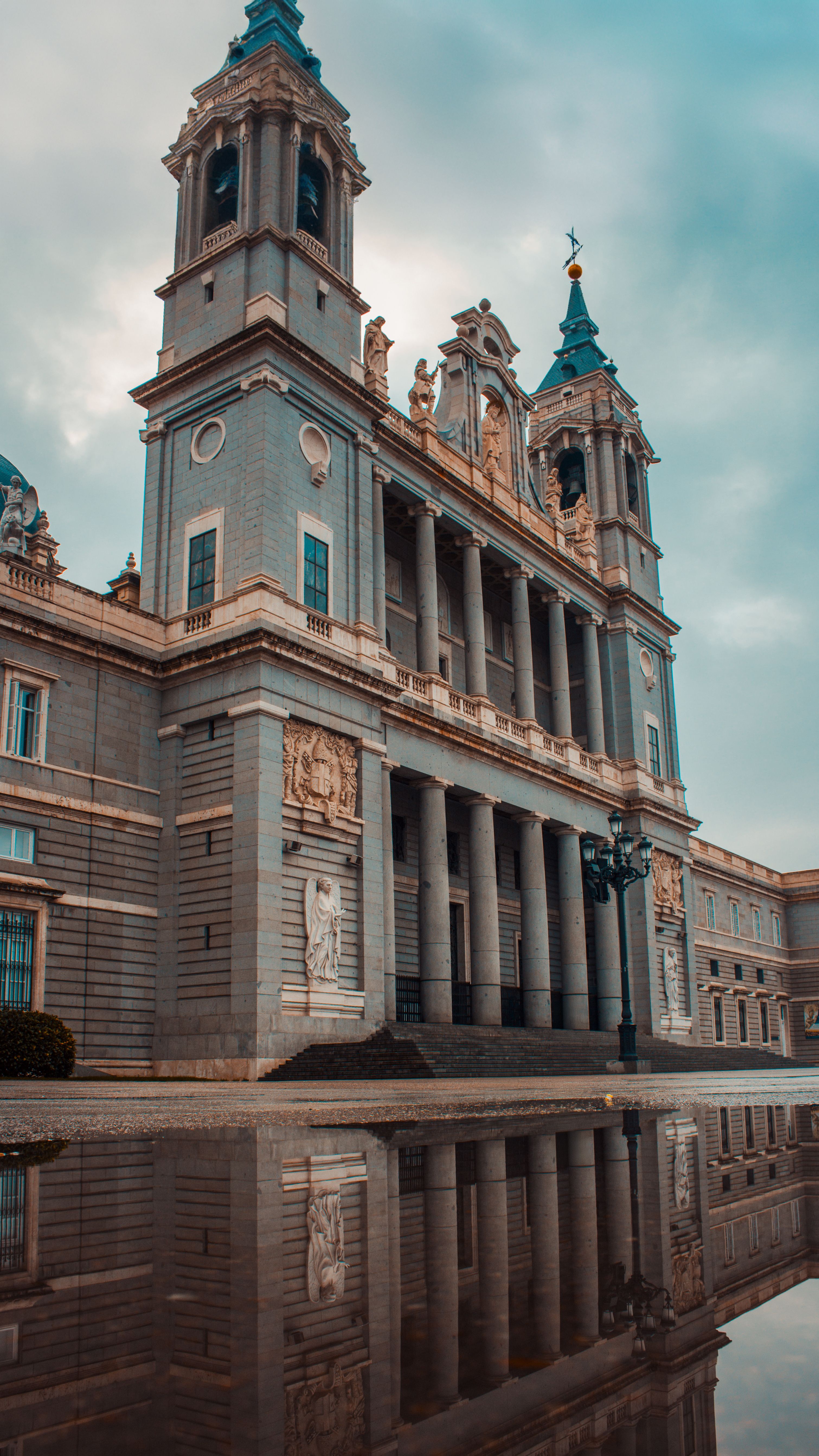 Elegant architectural view of Almudena Cathedral reflecting in puddle in Madrid, Spain.