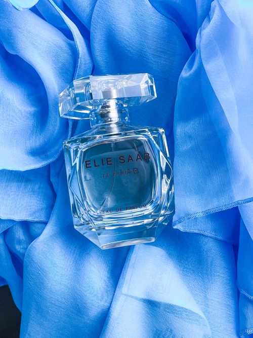 Free A stylish Elie Saab perfume bottle displayed on luxurious blue fabric, exuding elegance. Stock Photo