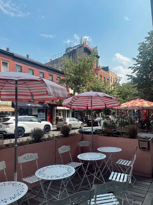 Free Charming outdoor café seating with striped umbrellas on a bustling New York City street. Stock Photo