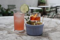 Two refreshing cocktails and a bowl of snacks on a marble table. Perfect for a casual outdoor setting.
