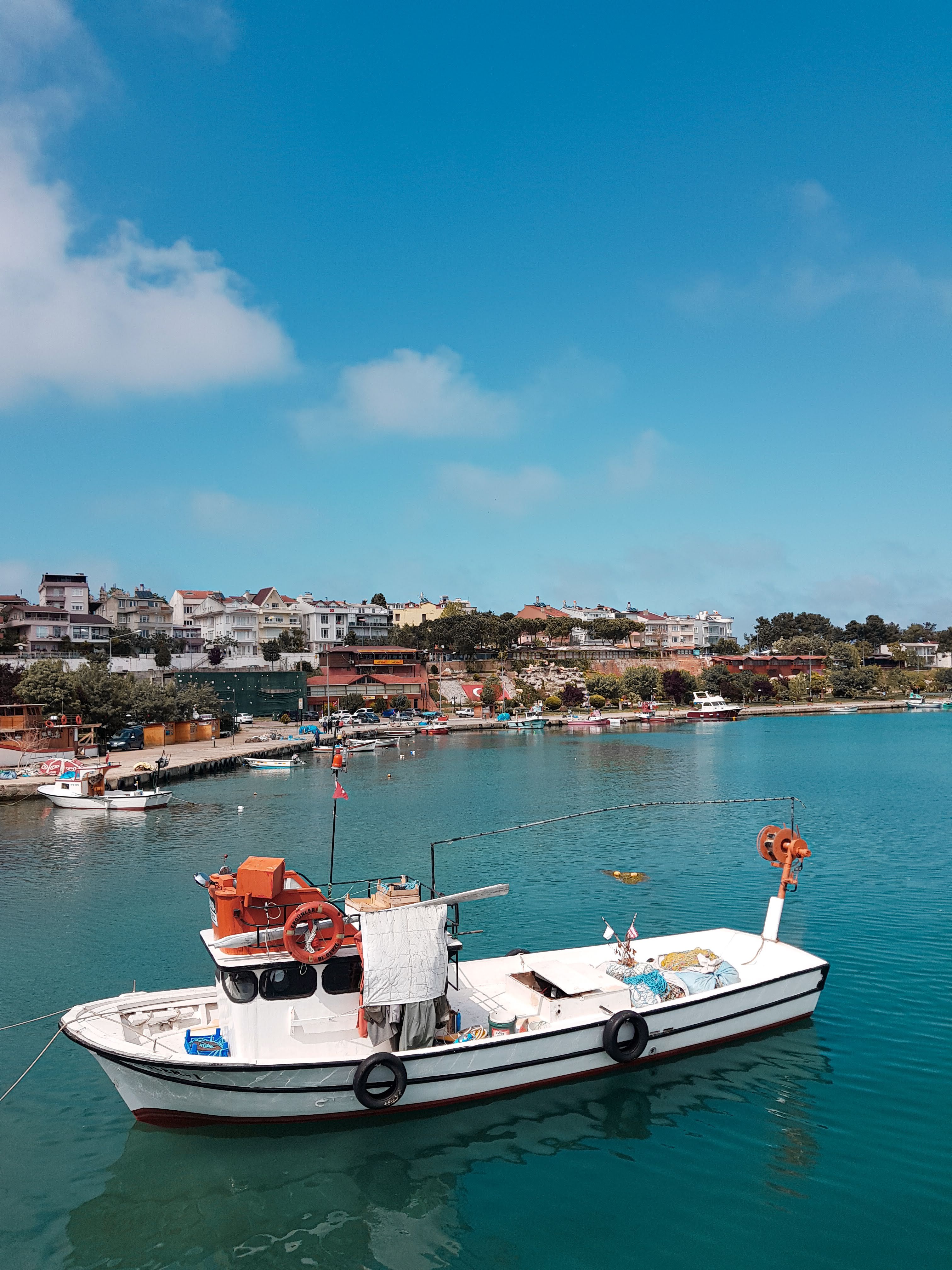 A picturesque view of a moored fishing boat in a serene harbor under a clear blue sky.