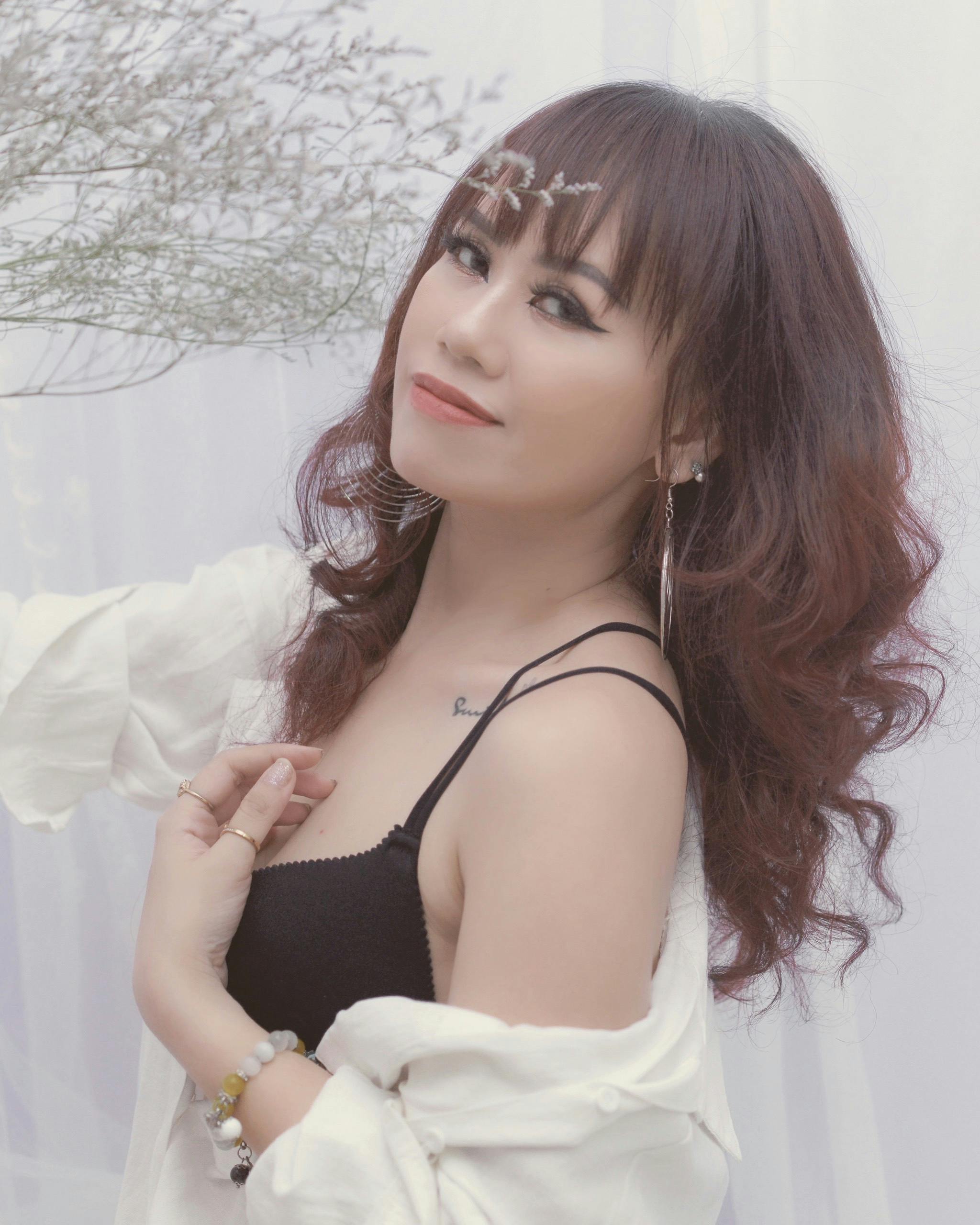 A young woman in a white shirt smiles serenely, showcasing casual elegance.