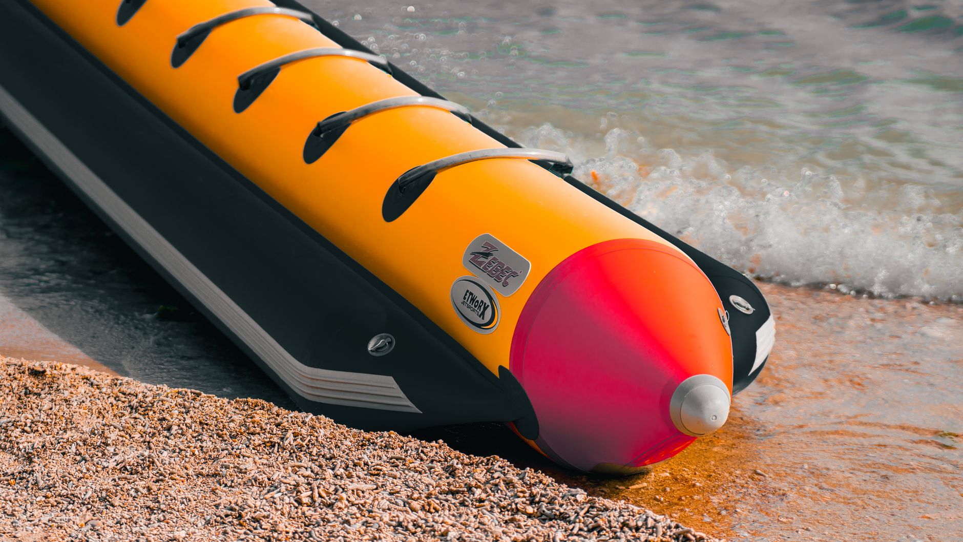 Vibrant yellow and red inflatable banana boat at the shoreline, perfect for beach fun.