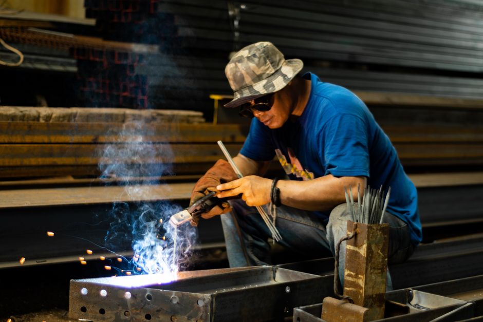 A skilled welder wearing protective gear operates in an industrial setting, highlighting craftsmanship and safety.