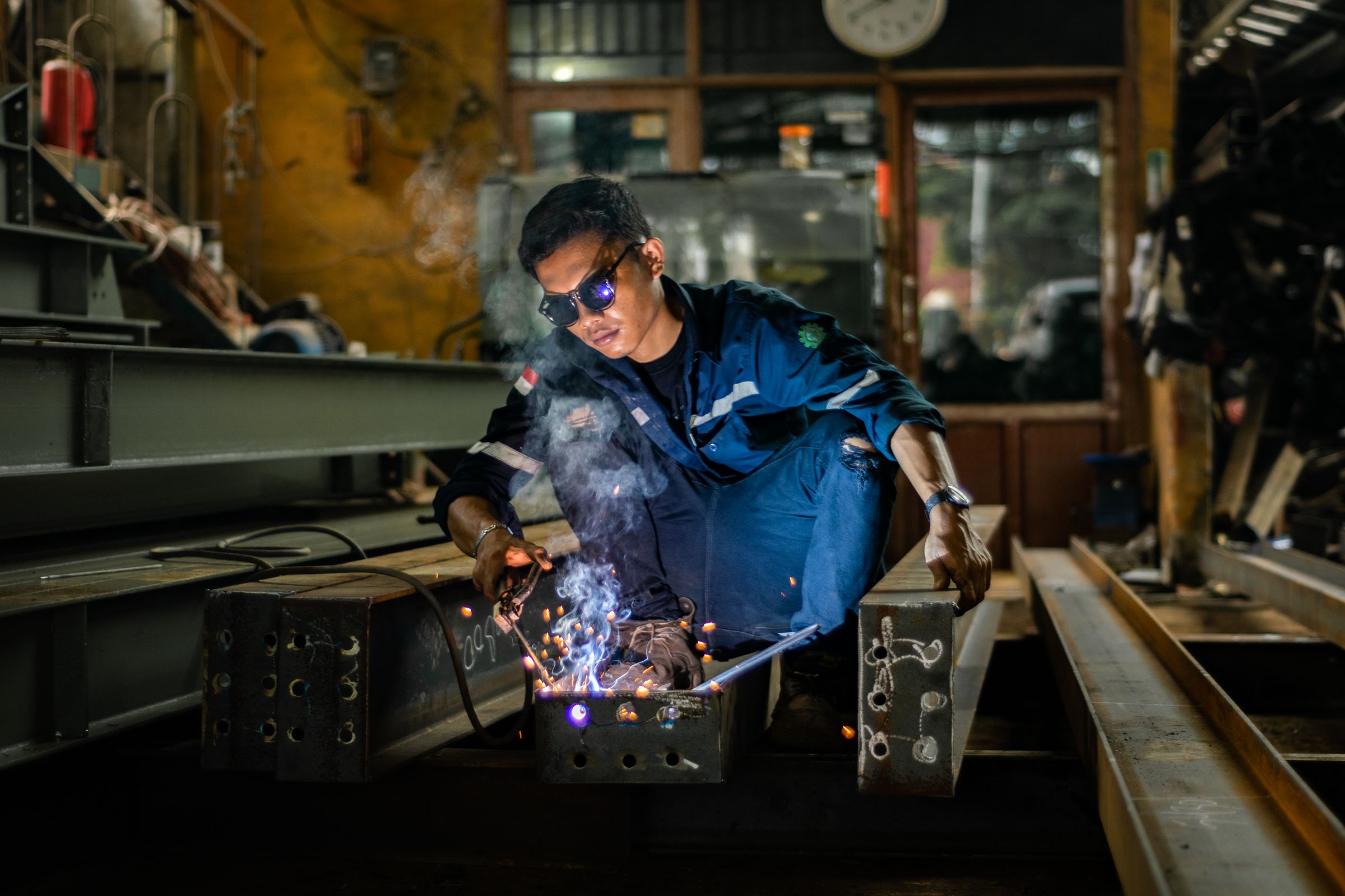 Welder in workshop running torch on metal