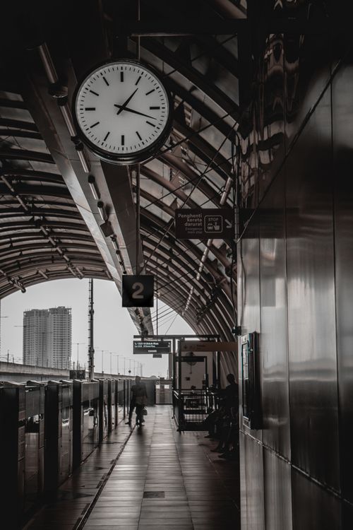 Free A moody urban railway station platform with a prominent clock under a curved roof. Stock Photo