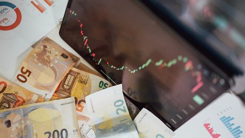 Close-up of euro banknotes with a digital stock market chart displaying a downward trend, symbolizing financial volatility.