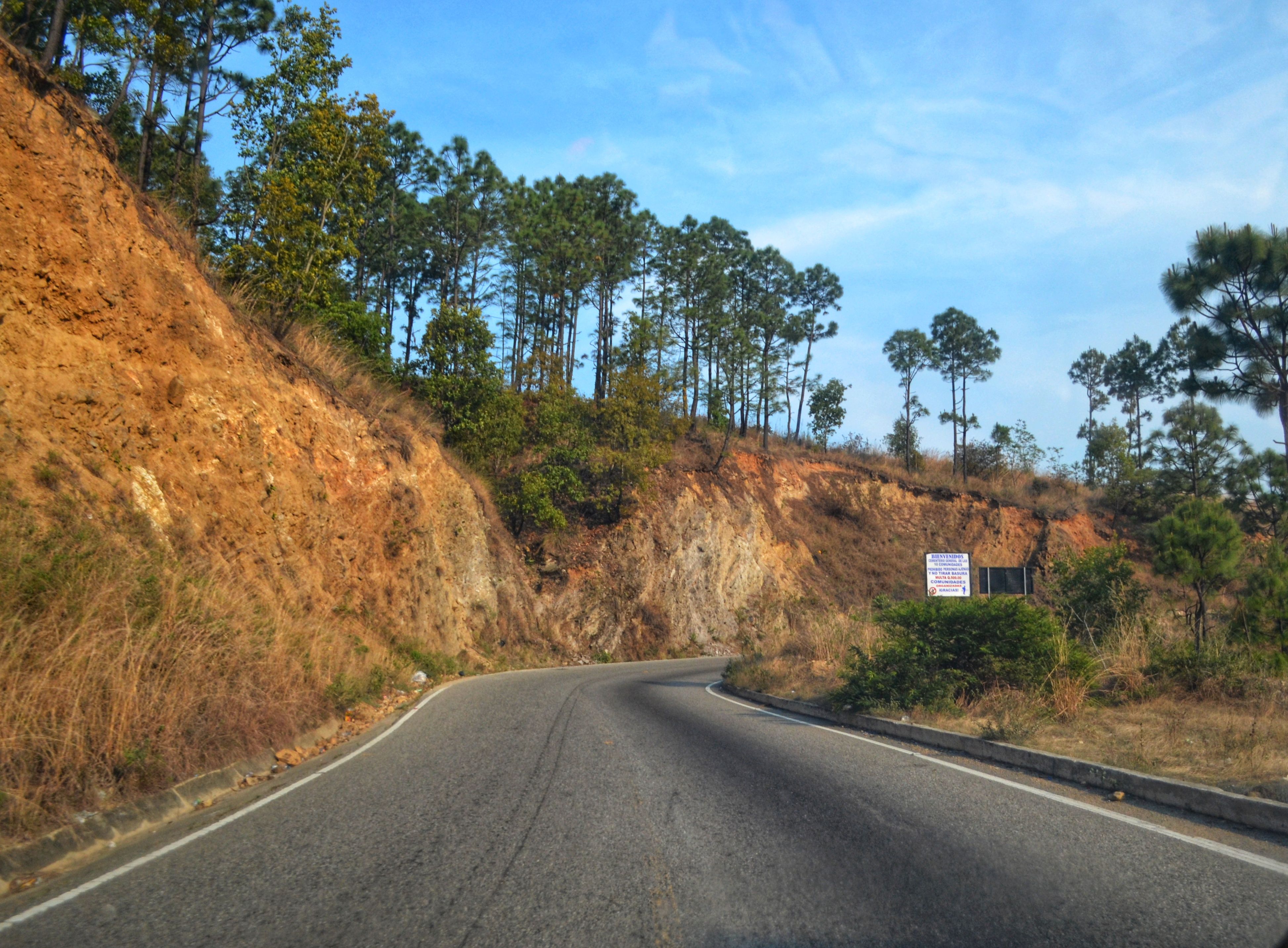 Empty two-lane road curving through green hills north of Mumbai