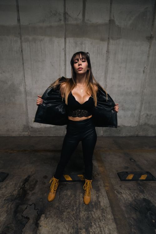 Free Stylish woman posing in a parking garage wearing lace top and leather jacket. Stock Photo