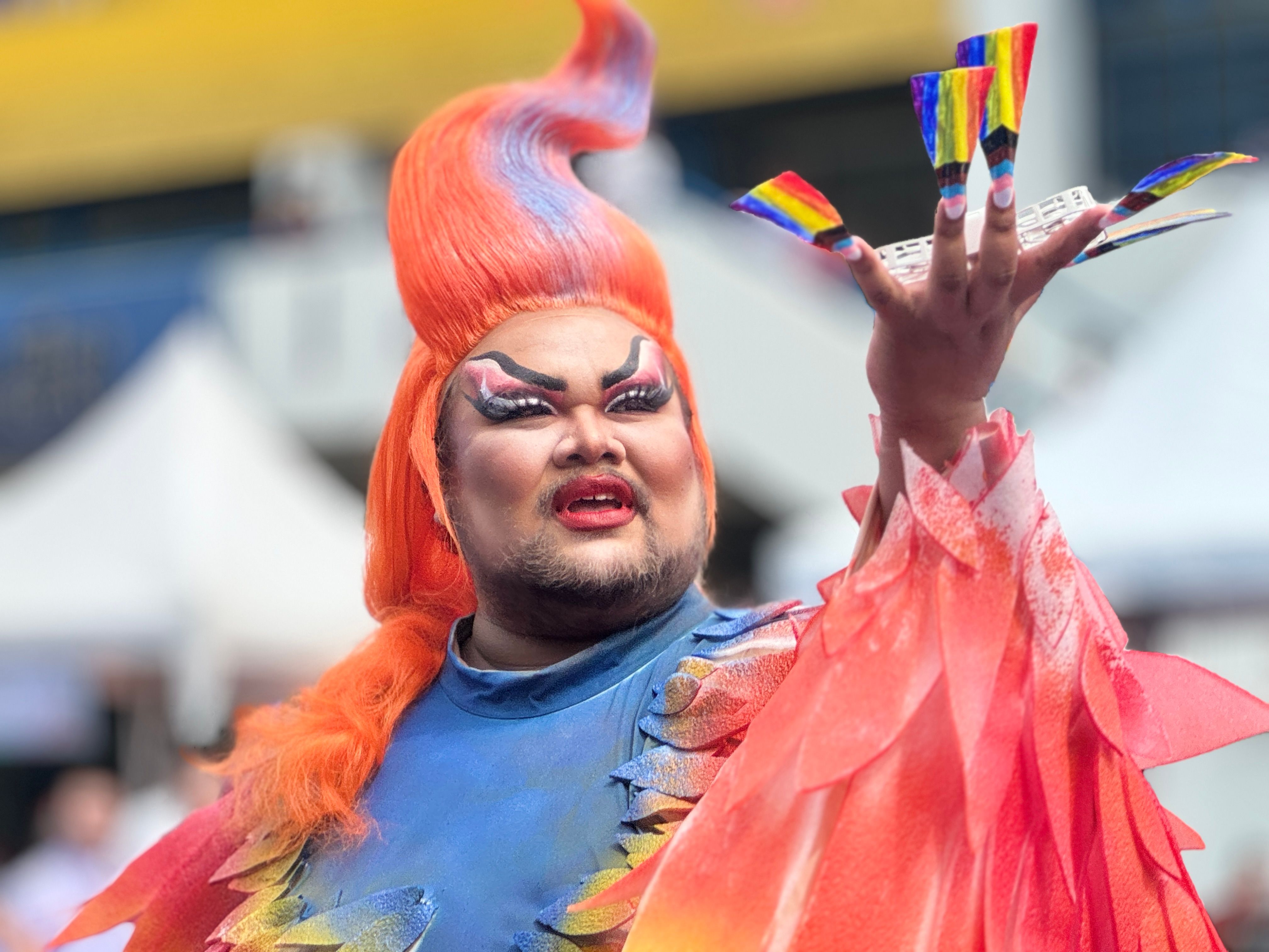 Colorful drag queen with rainbow nails at a pride parade in Bangkok.