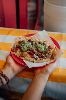 Close-up of a Mexican taco with green salsa, served on a red plate, in Ciudad de México.