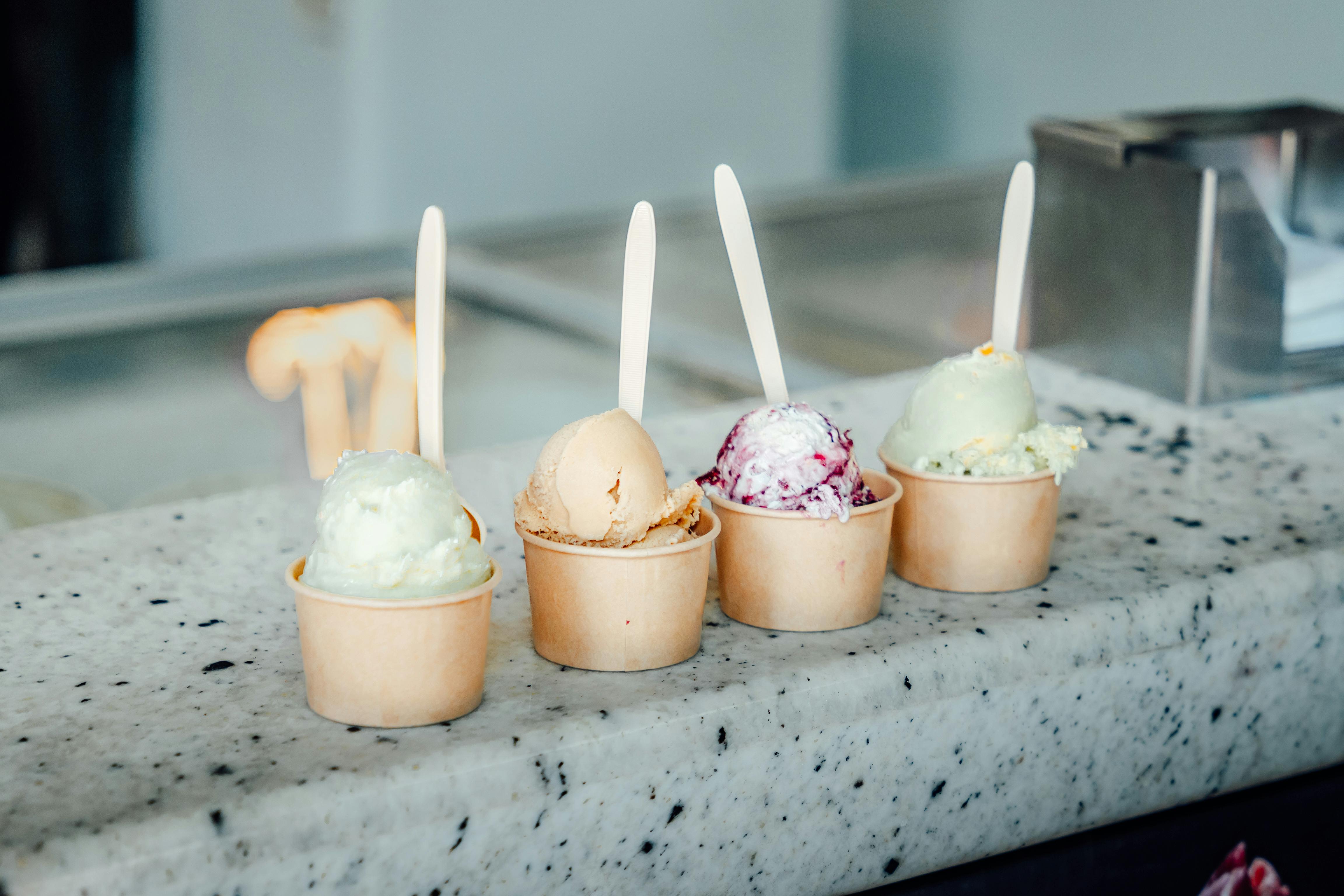 Vibrant ice cream scoops in cups with spoons, perfect for dessert lovers in a Mexican ice cream shop.