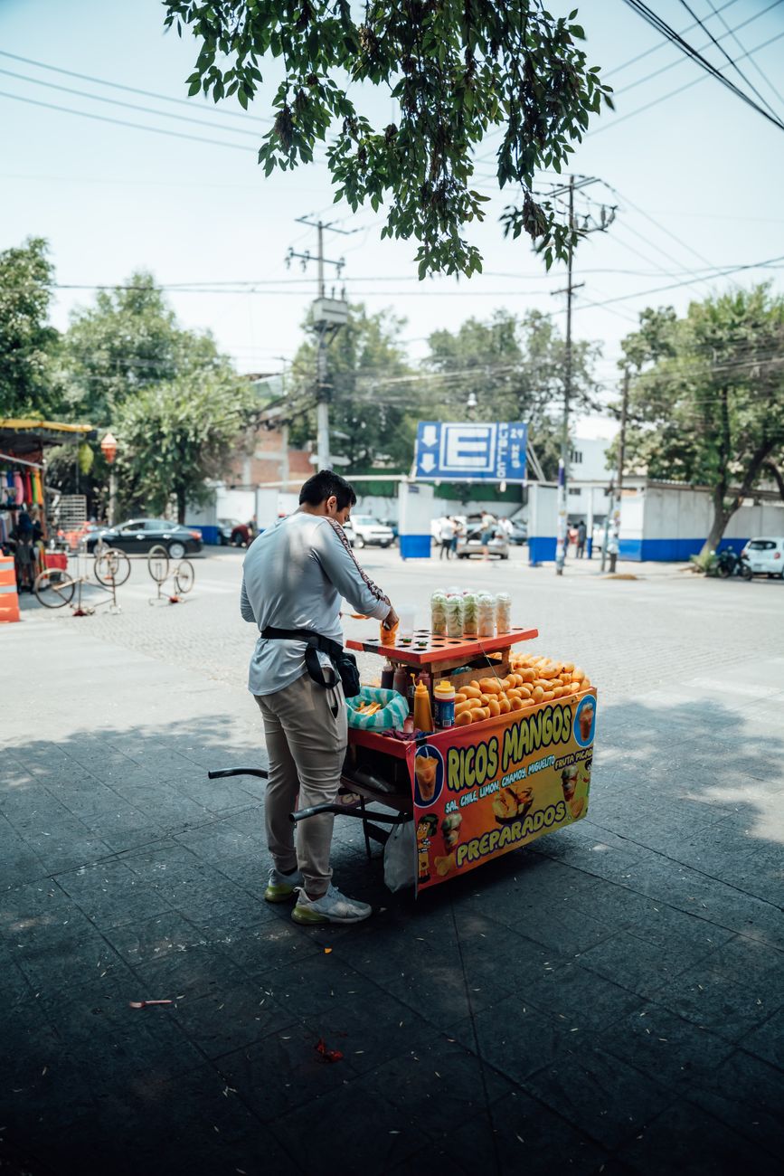 Street vendor selling mango snacks at a colorful cart in Mexico City