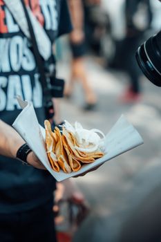 Close-up of a person holding tacos with onion on paper in the streets of Ciudad de México.