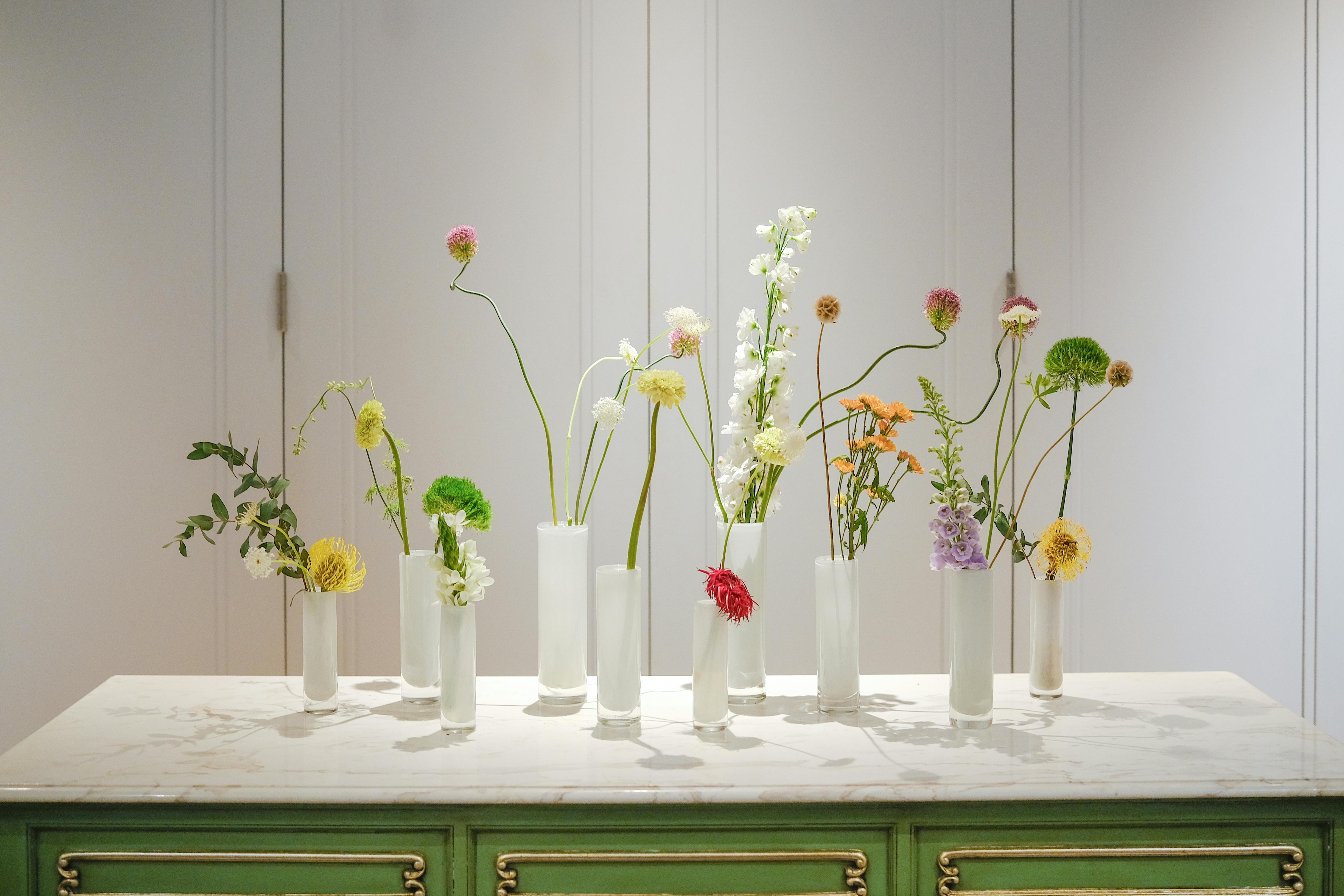 Elegant minimalist floral arrangement with diverse flowers in vases on a table.
