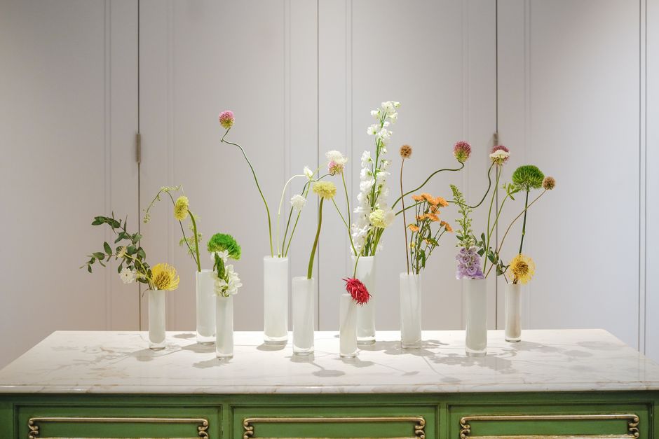 Elegant minimalist floral arrangement with diverse flowers in vases on a table.