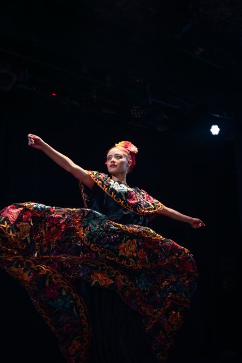 Free Colorful Mexican dancer performing on stage, showcasing traditional attire against a dark backdrop. Stock Photo