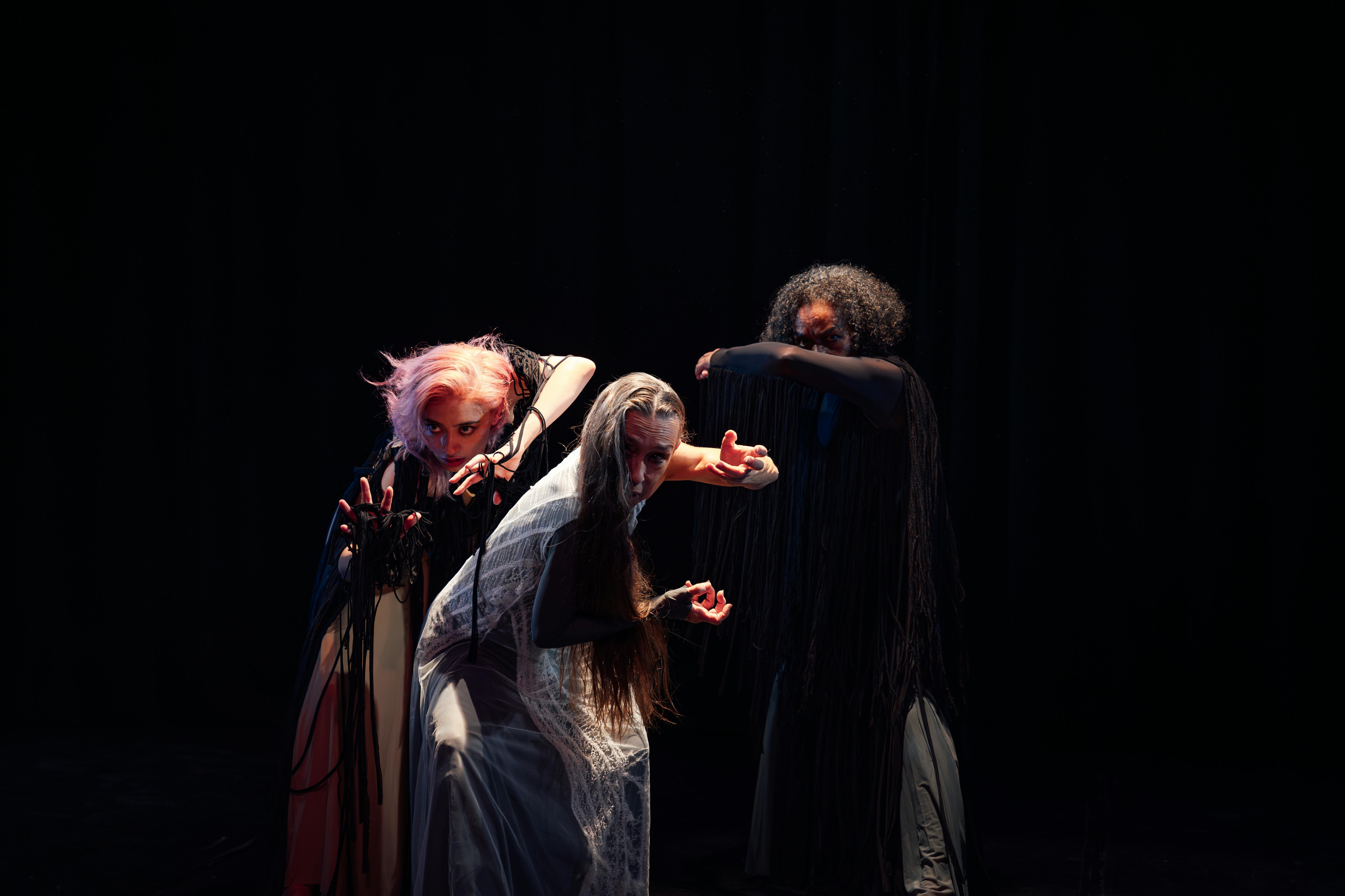 Free Three women in a theatrical dance performance on a dark stage in Ciudad de México. Stock Photo