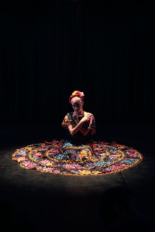 Free A woman in traditional clothing sits elegantly on a stage under spotlight, showcasing cultural fashion. Stock Photo