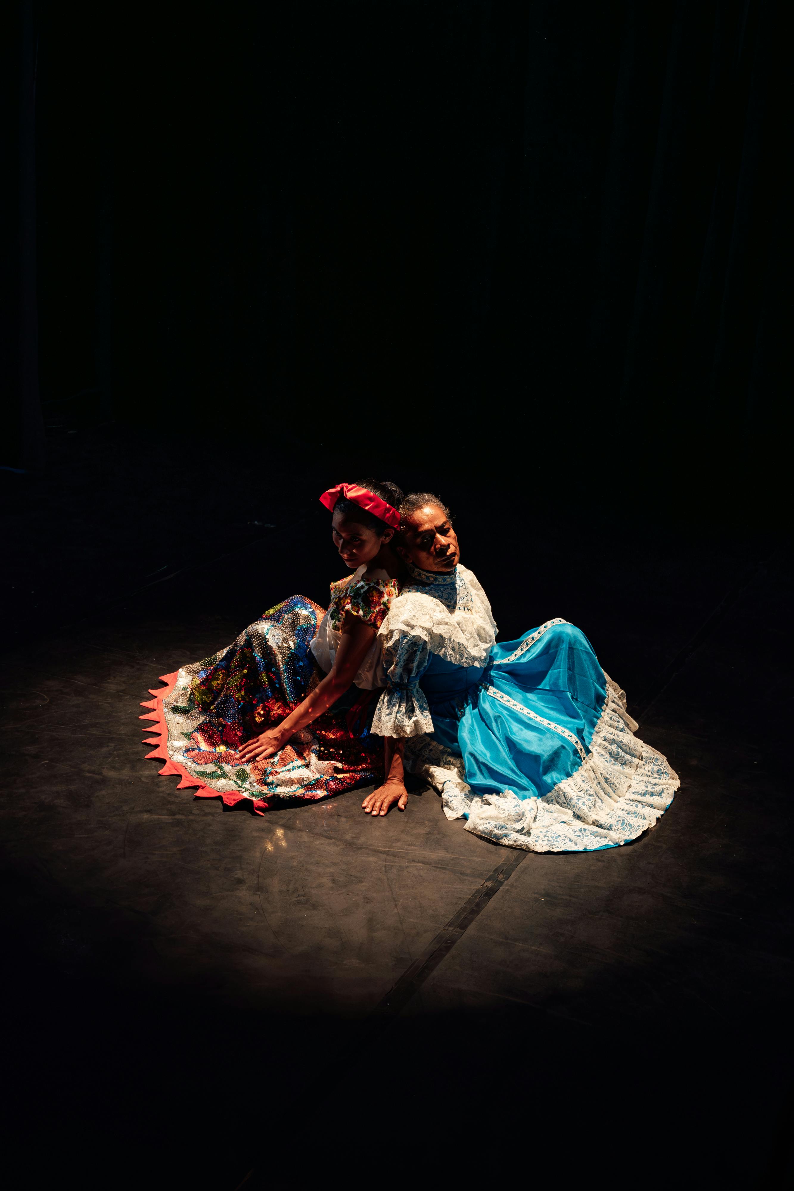 Free Traditional Mexican dancers in vibrant dresses on a dimly lit stage. Stock Photo
