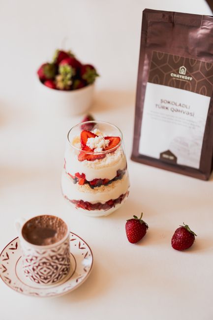 Elegant layered dessert with fresh strawberries, paired with rich coffee in artistic setting.