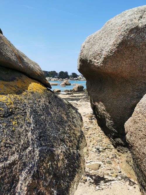 Free A tranquil beach scene with large boulders, blue sky, and summer sunlight creating a serene coastal landscape. Stock Photo