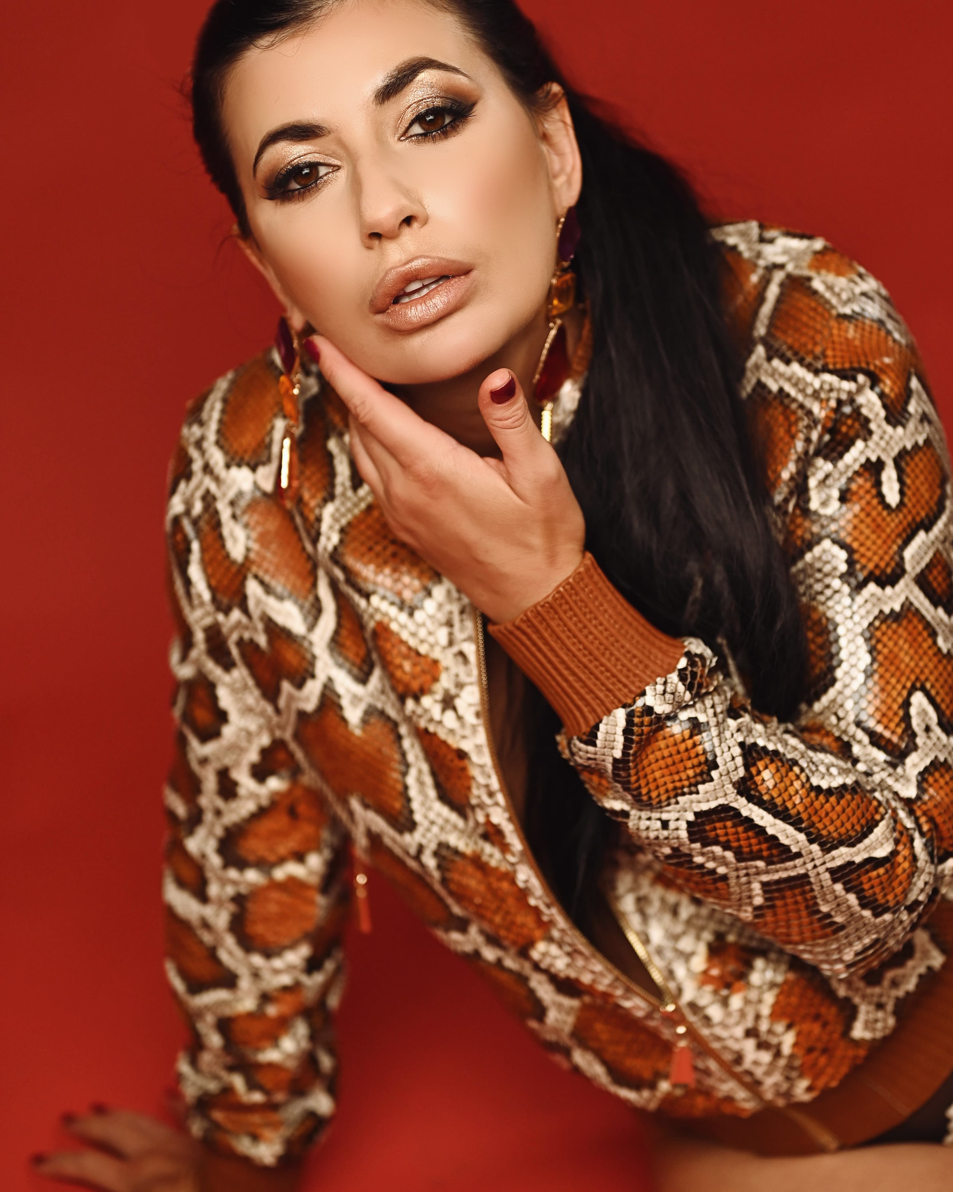Elegant woman posing in a striking snake skin pattern jacket showcasing glamorous fashion.