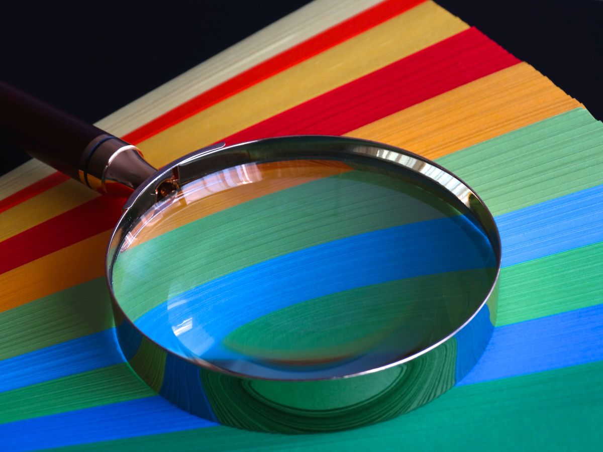 Colorful magnifying glass on vibrant rainbow paper, representing verifying urgency marketing claims